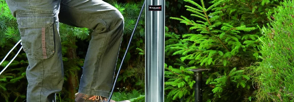 Person lässt Pumpe in Brunnen hinab